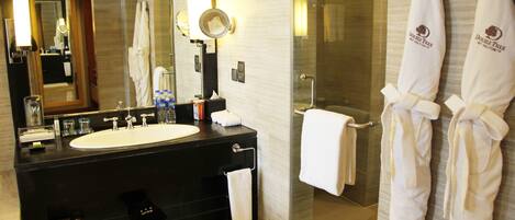Un baño moderno con un espejo grande, un lavamanos y una cabina de ducha de vidrio.