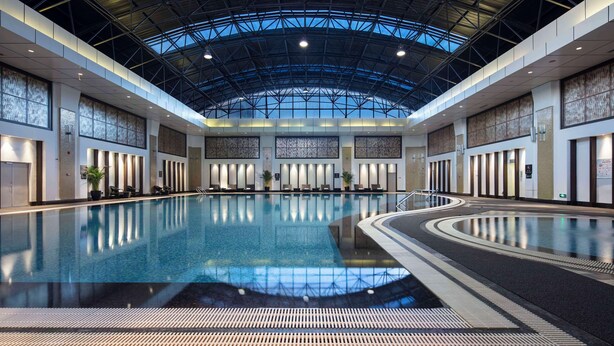 A large indoor swimming pool with a high ceiling and skylights, surrounded by seating areas and a modern architectural design. - DoubleTree by Hilton Hotel Shenyang (Shenyang)