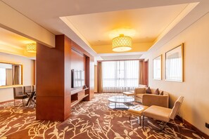 A hotel room with a large mirror, a television, a sofa, a coffee table, and a patterned carpet. - DoubleTree by Hilton Hotel Shenyang (Shenyang)