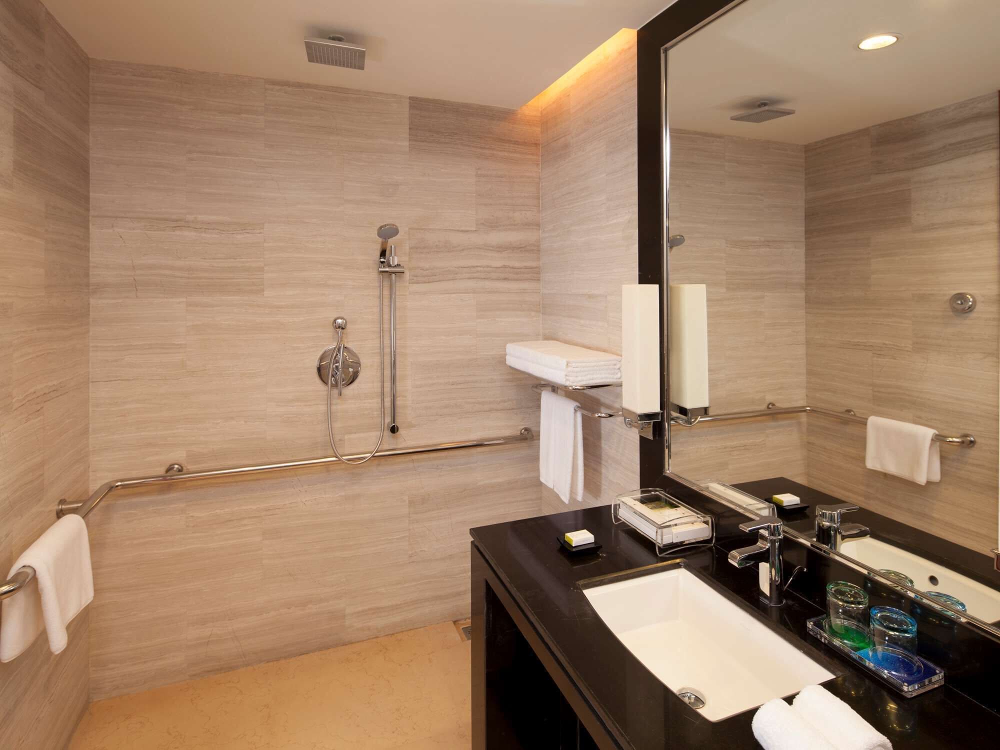 Un baño moderno con ducha a ras de suelo, tocador con lavabo y un espejo grande.