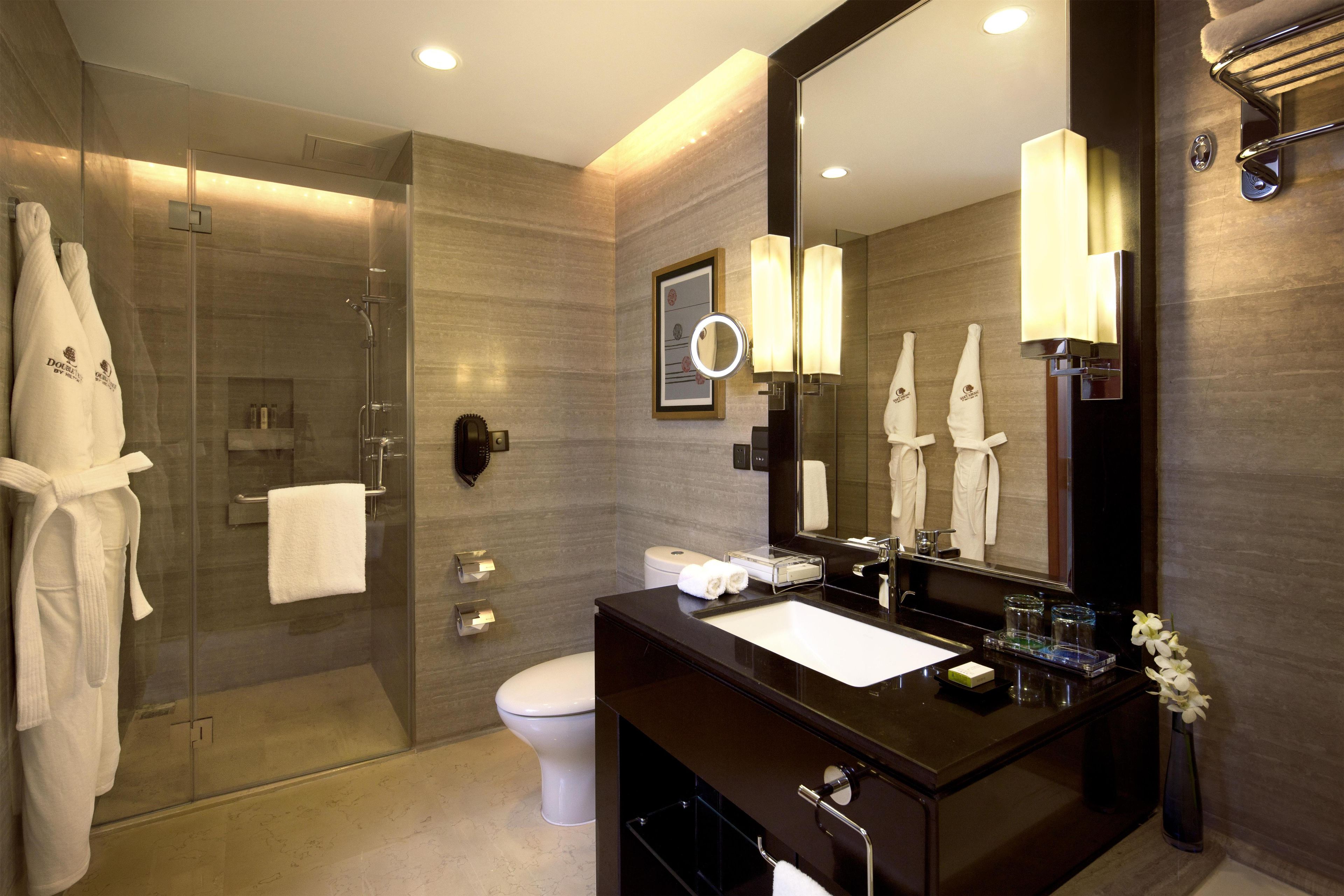A modern bathroom with a glass-enclosed shower, a vanity with a mirror, and a toilet.