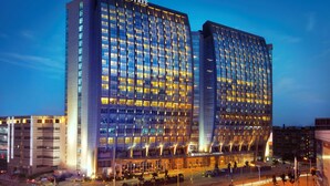 A modern hotel with a prominent "DOUBLETREE" sign, featuring a grid of windows and a curved facade. - DoubleTree by Hilton Hotel Shenyang (Shenyang)