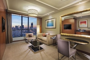 A hotel room with a large window offering a city view, a sofa, a chair, a small table, a flat-screen TV, and a minibar. - DoubleTree by Hilton Hotel Shenyang (Shenyang)