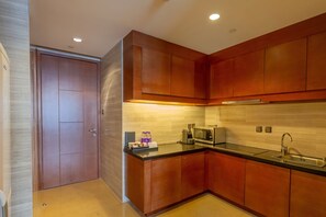 Una cocina moderna con armarios de madera, encimera negra, microondas empotrado y pileta de acero inoxidable.