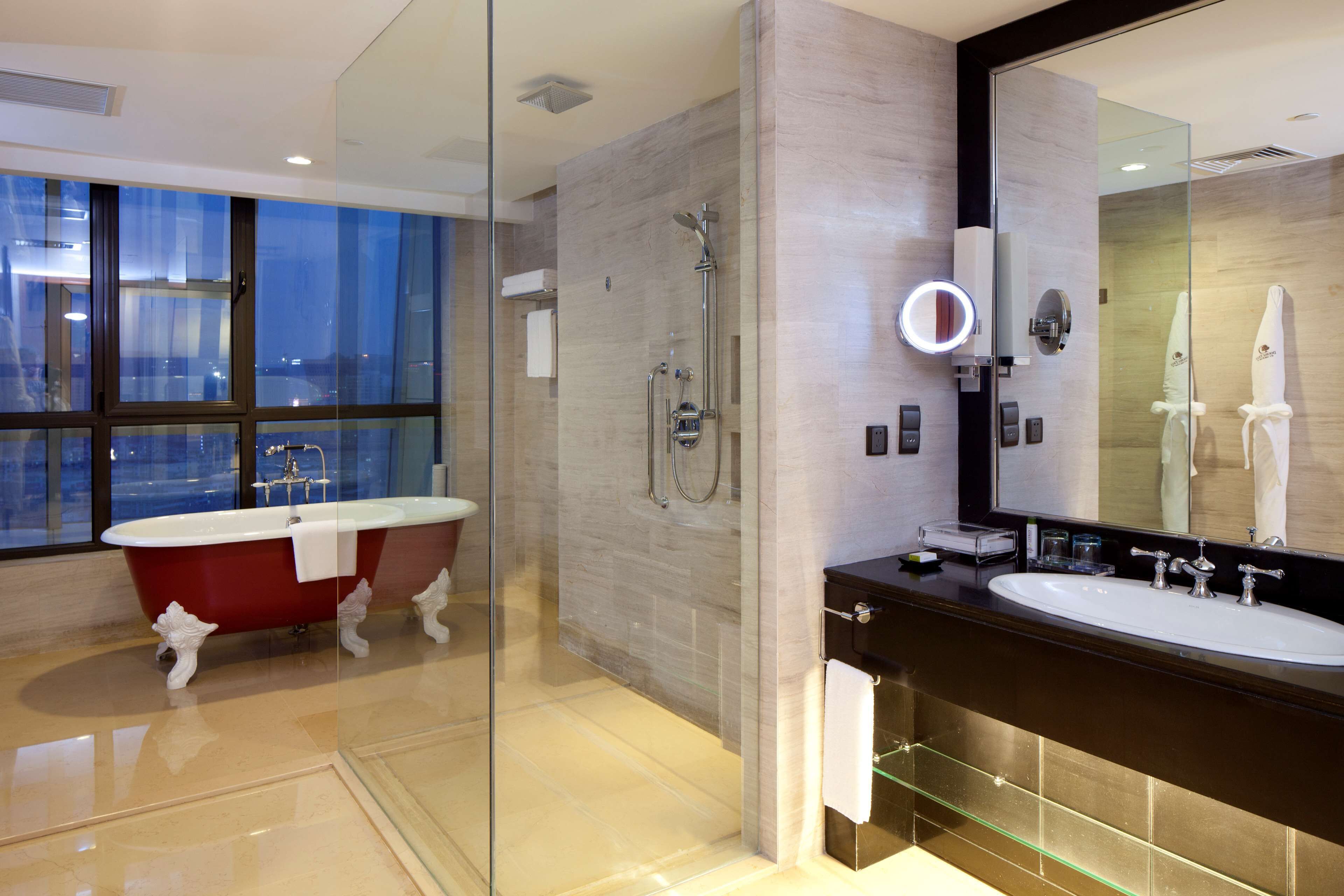 Une salle de bain moderne dotée d’une douche à parois de verre, d’une baignoire sur pieds et d’un grand miroir au-dessus du lavabo.