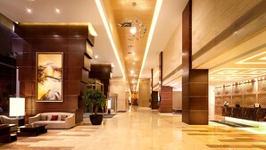 A spacious lobby with a marble floor, a reception desk, a large sofa, and a potted plant. - DoubleTree by Hilton Hotel Shenyang (Shenyang)
