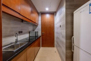Una cocina con gabinetes de madera, un lavamanos de acero inoxidable y un refrigerador blanco.
