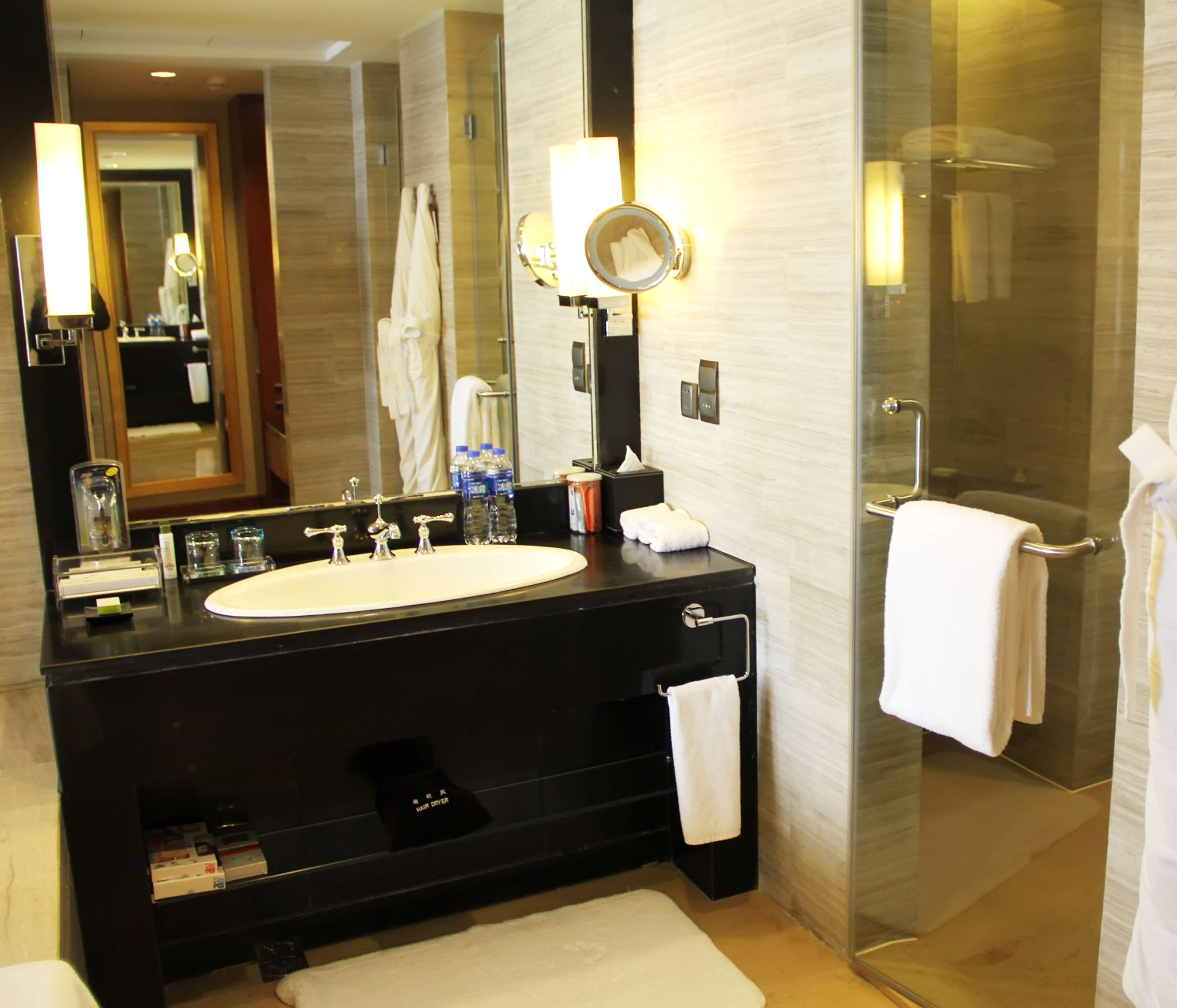 A modern bathroom with a large sink, mirror, and glass shower enclosure.