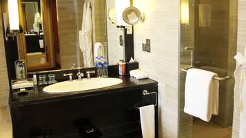 A modern bathroom with a large sink, mirror, and glass shower enclosure.