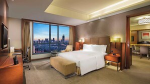 A hotel room with a large bed, a desk with a computer, a chair, a small table, and a view of a cityscape. - DoubleTree by Hilton Hotel Shenyang (Shenyang)