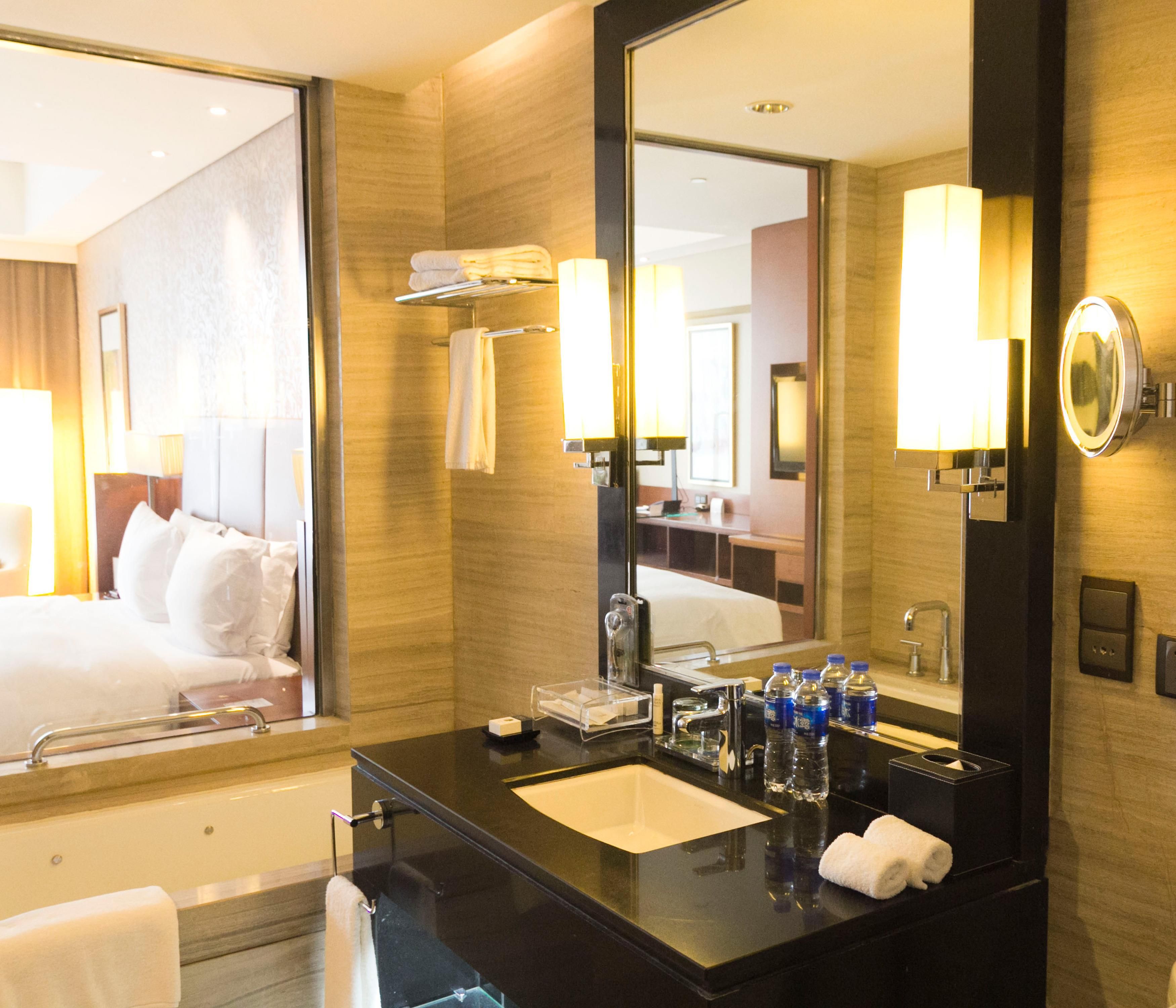 Une salle de bain d’hôtel avec un grand miroir, une baignoire, un lavabo et un porte-serviettes.