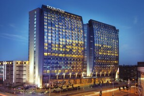 A large, modern hotel with a prominent 'DOUBLETREE' sign, featuring a grid of windows and a curved facade. - DoubleTree by Hilton Hotel Shenyang (Shenyang)