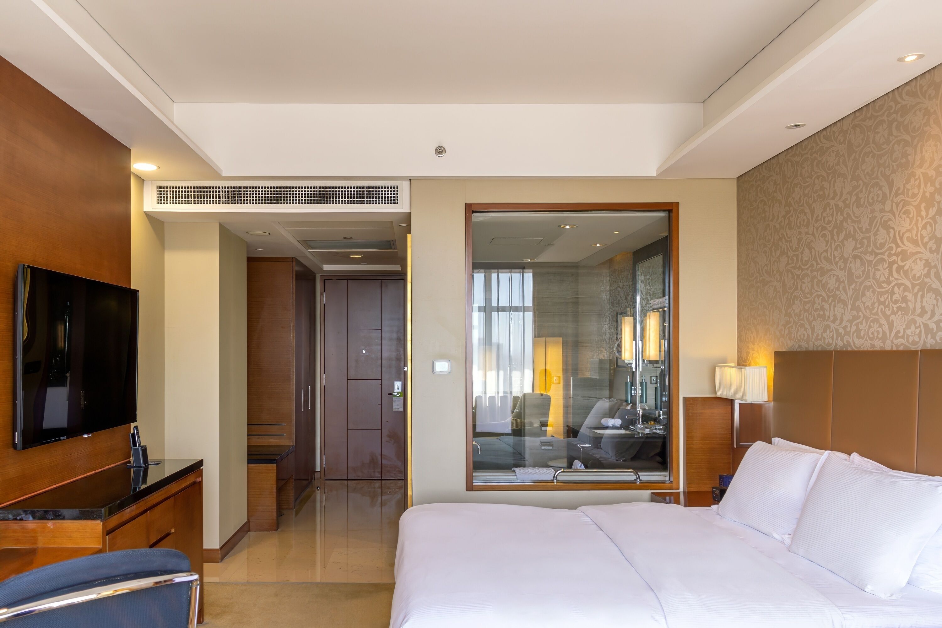 Habitación de hotel con una cama grande, un televisor de pantalla plana, un escritorio y un espejo.