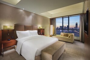 A hotel room with a large bed, a sofa, a city view, and a TV. - DoubleTree by Hilton Hotel Shenyang (Shenyang)