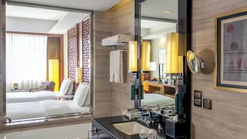 A hotel room with a large bed, a bathroom with a black sink and mirror, and a view of the outside.