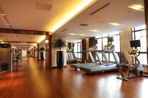 A gym with treadmills, exercise bikes, and a large potted plant. - DoubleTree by Hilton Hotel Shenyang (Shenyang)