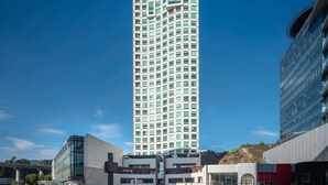 A tall, modern building with a grid of windows, surrounded by other contemporary structures. - The Paragon Hotel Mexico City Santa Fe By Accor (Mexico City)