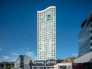 En høj, moderne bygning med et vinduesgitter, omgivet af andre moderne bygninger.