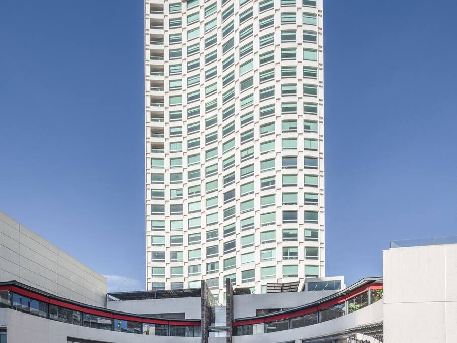 A tall, modern hotel with a curved facade and numerous windows.
