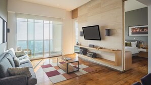 A modern living room with a large TV, wooden flooring, and a sofa. - The Paragon Hotel Mexico City Santa Fe By Accor (Mexico City)