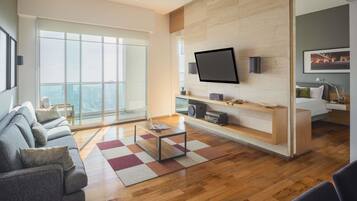 Una sala de estar moderna con un televisor grande, piso de madera y un sofá.