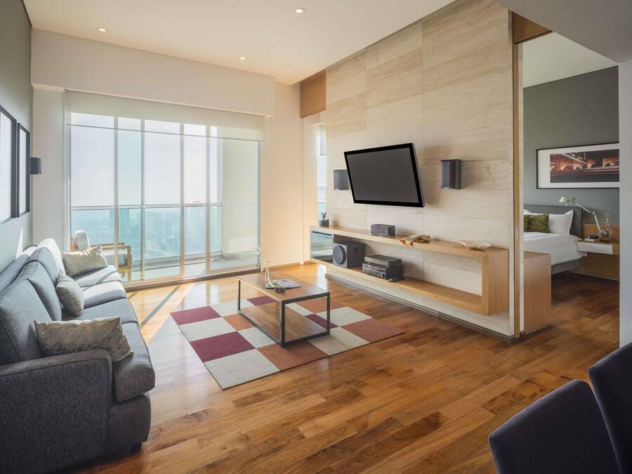 Una sala de estar moderna con un televisor grande, piso de madera y un sofá.