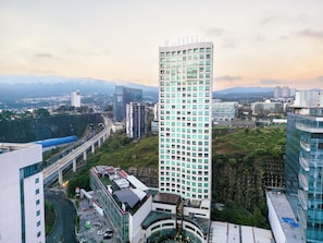 Un edificio moderno de gran altura con fachada de vidrio, rodeado de otros edificios y una autopista.