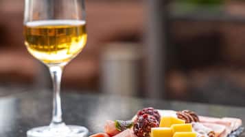 Ein Glas Weißwein und eine Wurstplatte mit verschiedenen Käsesorten, Früchten und Fleisch.