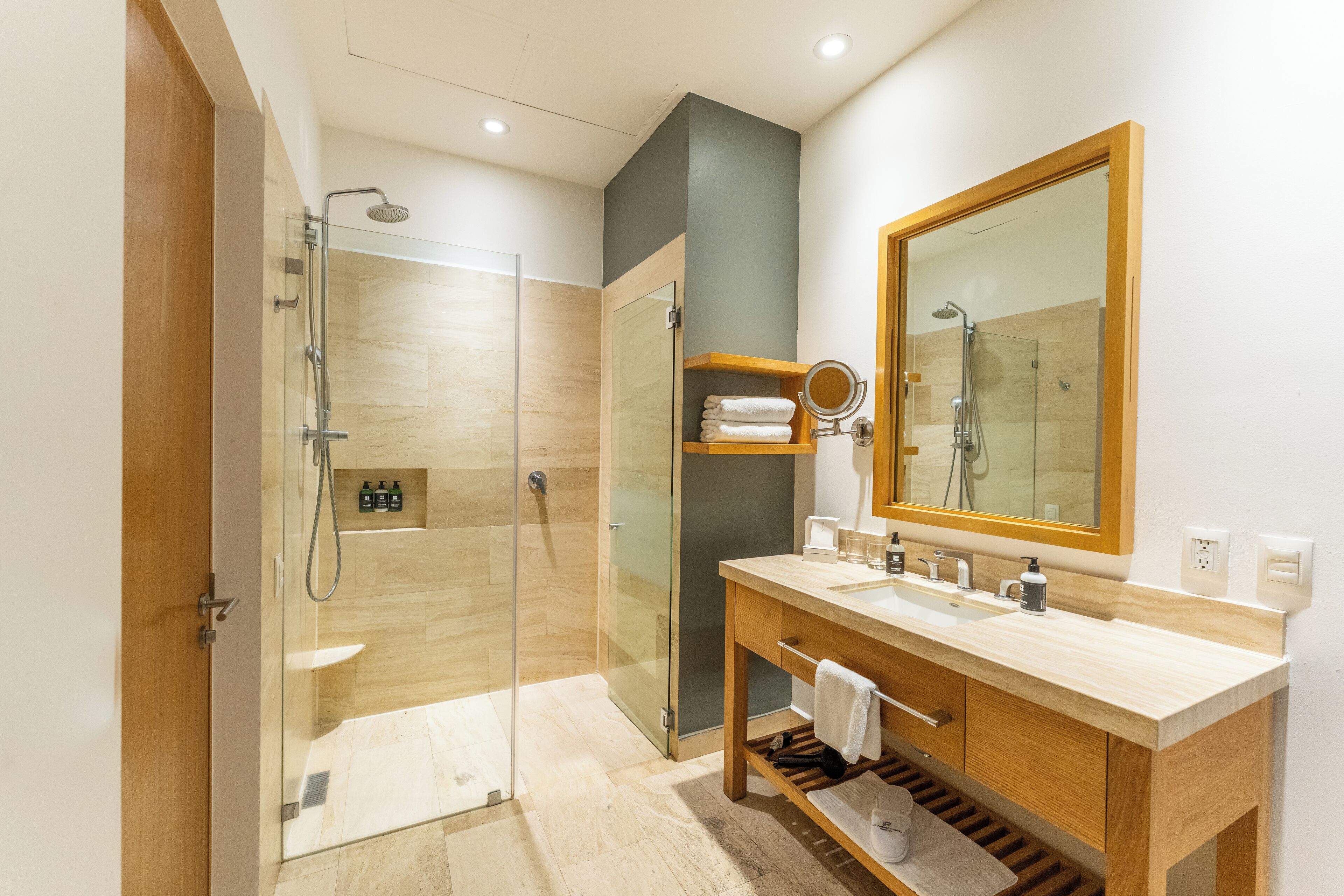 A modern bathroom with a glass-enclosed shower, wooden vanity, and a large mirror.
