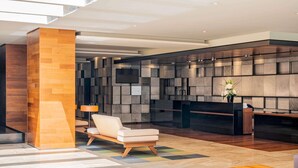 A modern lobby with a reception desk, seating area, and a large wall with a geometric pattern. - The Paragon Hotel Mexico City Santa Fe By Accor (Mexico City)