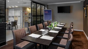 A conference room with a long table, chairs, a glass partition, and a poster on the wall. - Holiday Inn Express Amsterdam - South by IHG (Amsterdam)