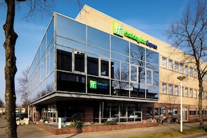 Moderni rakennus, jossa on lasijulkisivu, Holiday Inn Express -kyltti ja kirkkaan sininen taivas.
