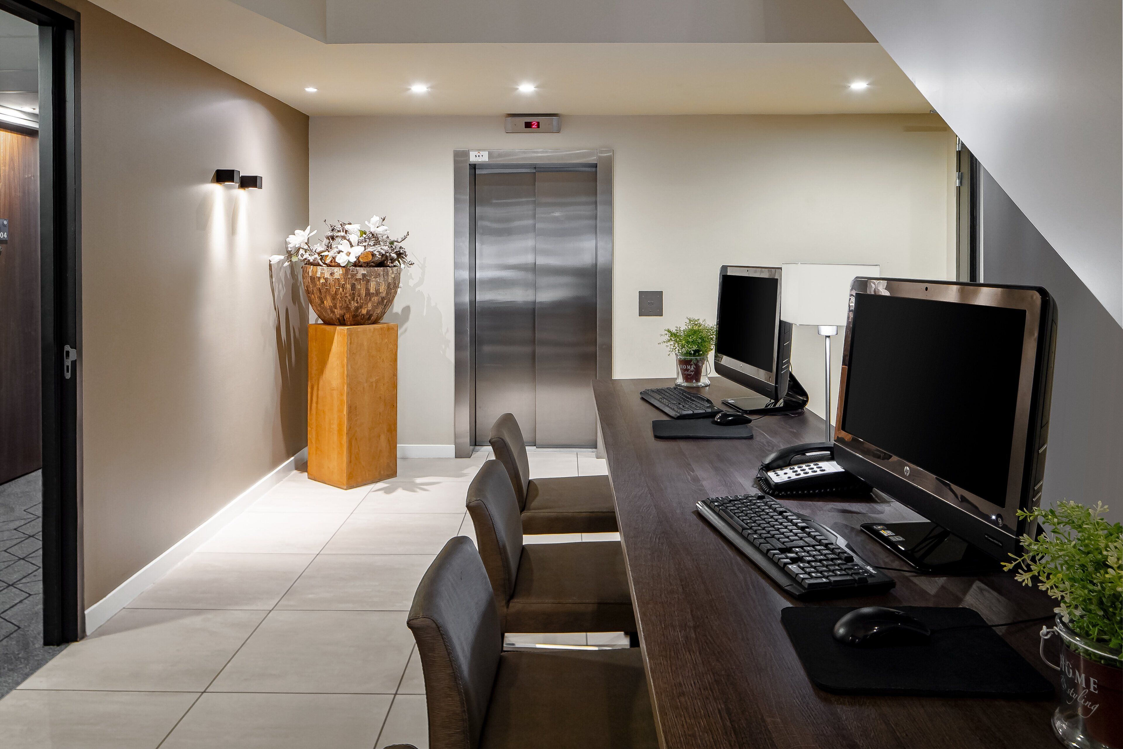 Een moderne kantoorruimte met een bureau, computer, toetsenbord, muis en een plant.