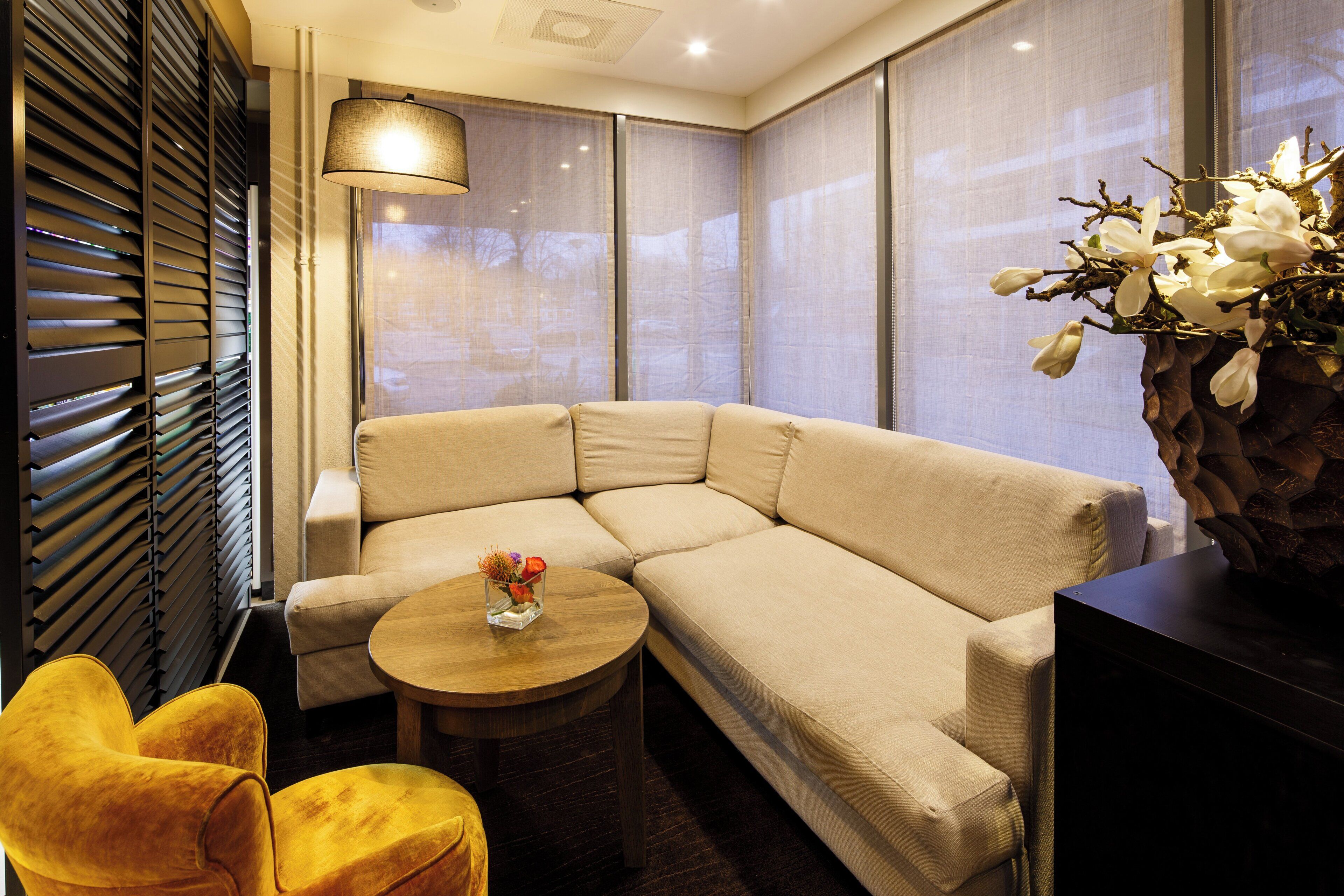 A modern living room with a beige sectional sofa, a small wooden coffee table, and a yellow armchair.