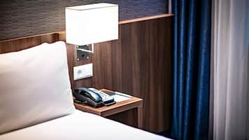 A hotel room with a wooden headboard, a bedside lamp, a telephone, and a white pillow.