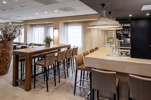A modern bar area with a long counter, multiple stools, and a bar tap. - Holiday Inn Express Amsterdam - South by IHG (Amsterdam)