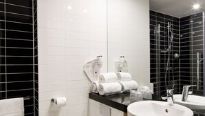 A modern bathroom with a white toilet, a sink, and a mirror. There are towels and toiletries on the counter. - Holiday Inn Express Amsterdam - South by IHG (Amsterdam)