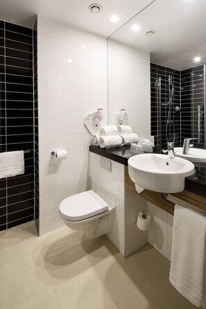 A modern bathroom with a white toilet, a sink, and a mirror. There are towels and toiletries on the counter. - Holiday Inn Express Amsterdam - South by IHG (Amsterdam)