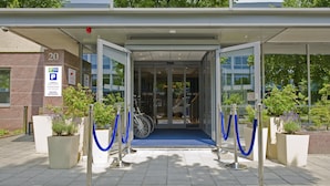 A hotel entrance with a blue carpet, glass doors, and a number 20 sign. - Holiday Inn Express Amsterdam - South by IHG (Amsterdam)