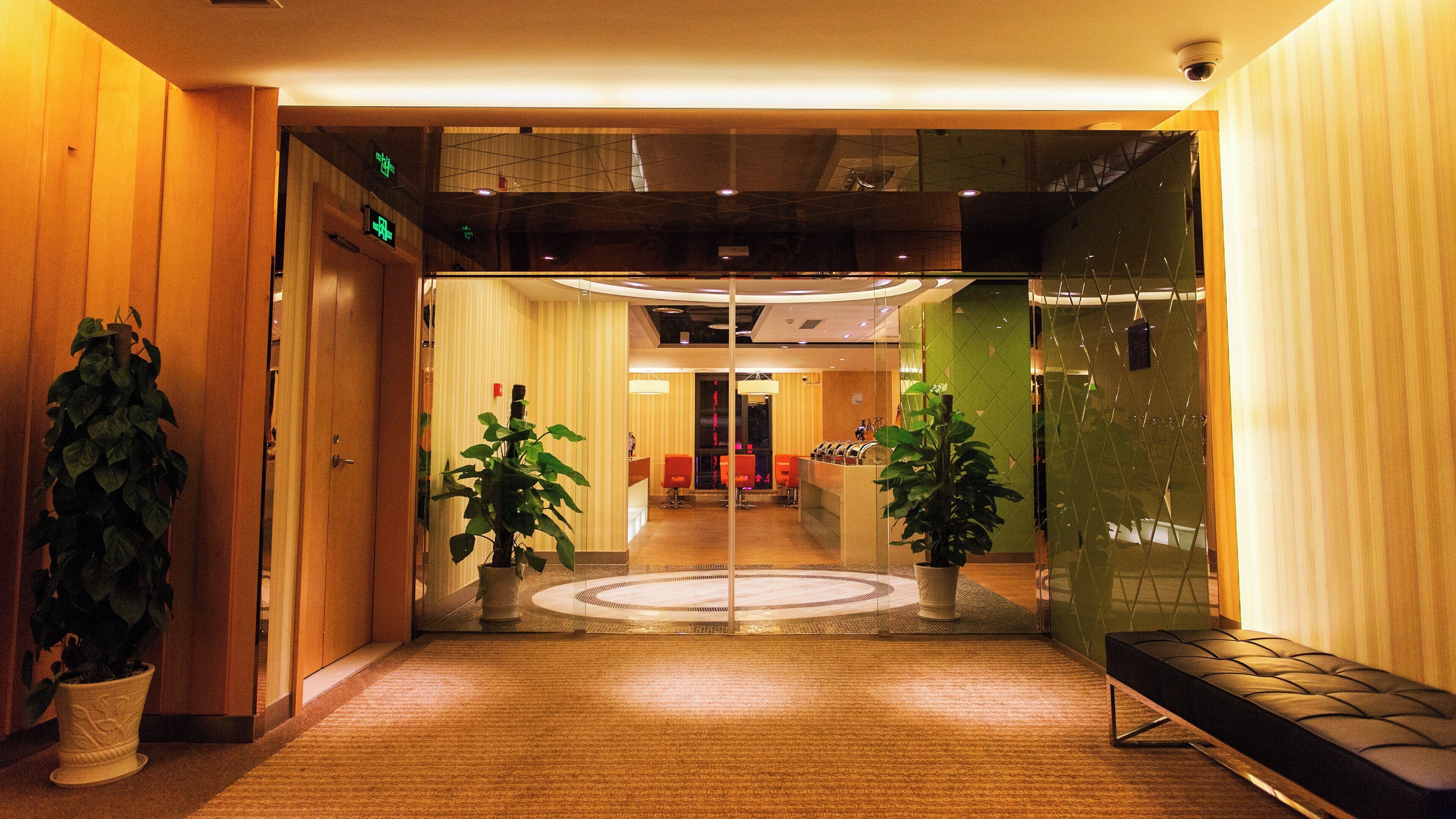 A hotel lobby with a reception desk, seating area, and potted plants.