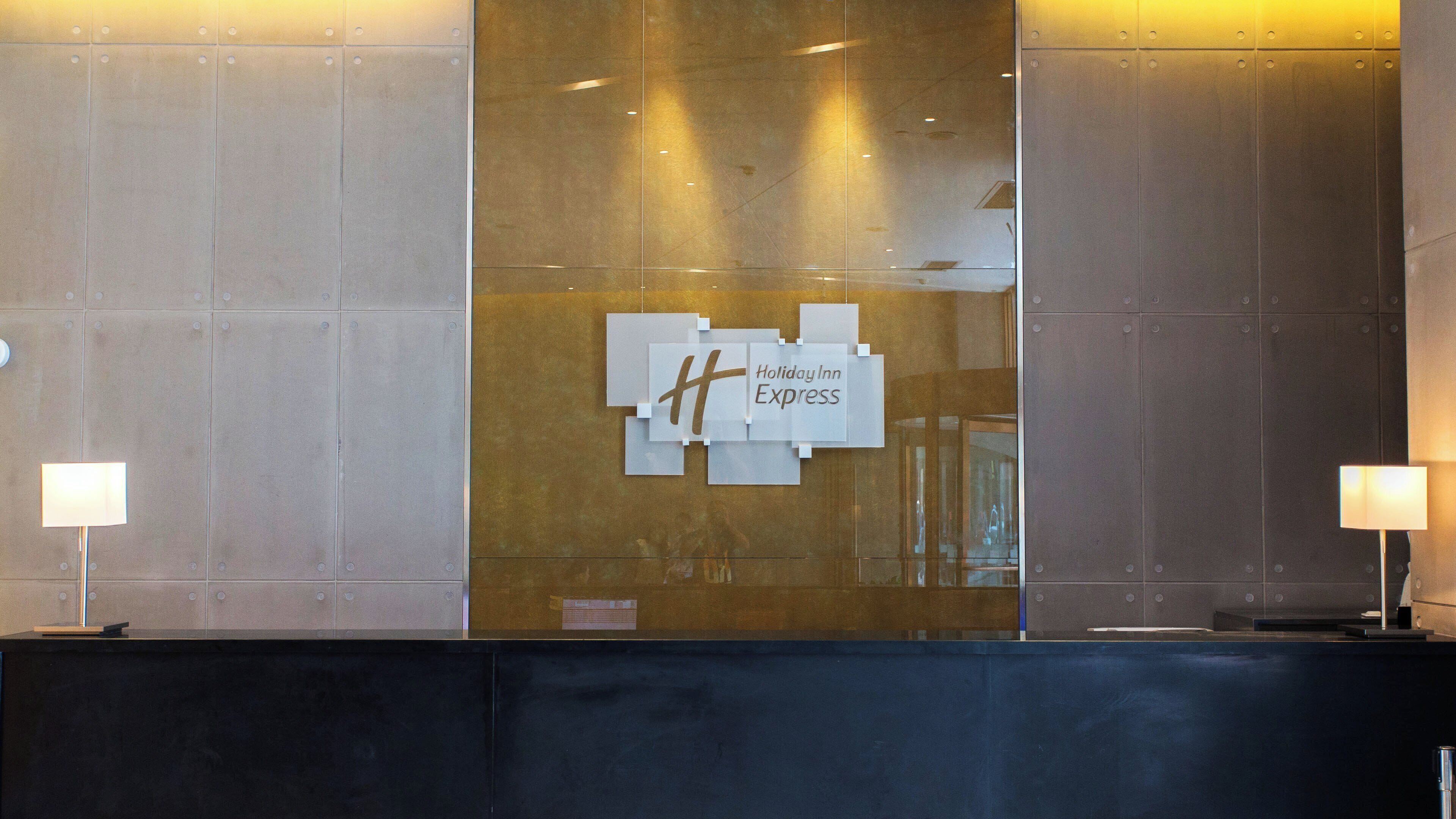A reception desk with a Holiday Inn Express sign, a glass partition, and two lamps.