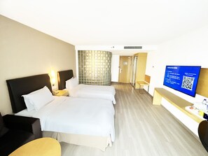 Et hotelværelse med to senge, et fjernsyn og et lille skrivebord.