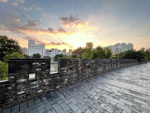 A stone wall with a paved walkway, leading to a cityscape with modern buildings under a sunset sky. - Holiday Inn Express Changzhou Center by IHG (Changzhou)