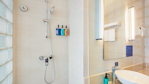 Un baño moderno con cabina de ducha de vidrio, un lavabo blanco y un espejo grande.