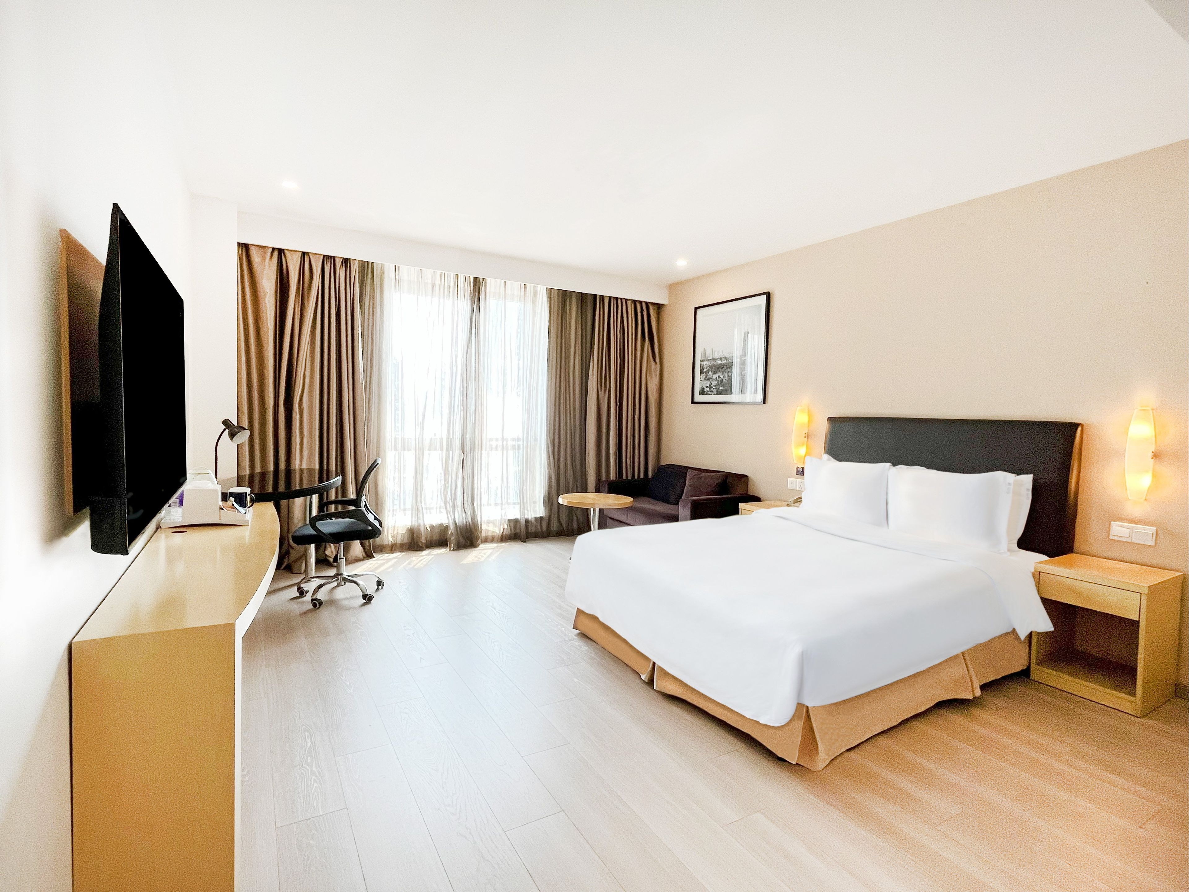 A hotel room with a bed, desk, chair, television, and curtains.
