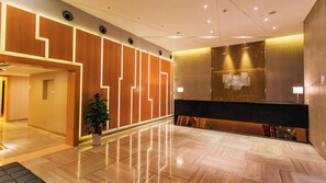 A modern hotel lobby with a reception desk, a potted plant, and a polished wooden floor. - Holiday Inn Express Changzhou Center by IHG (Changzhou)