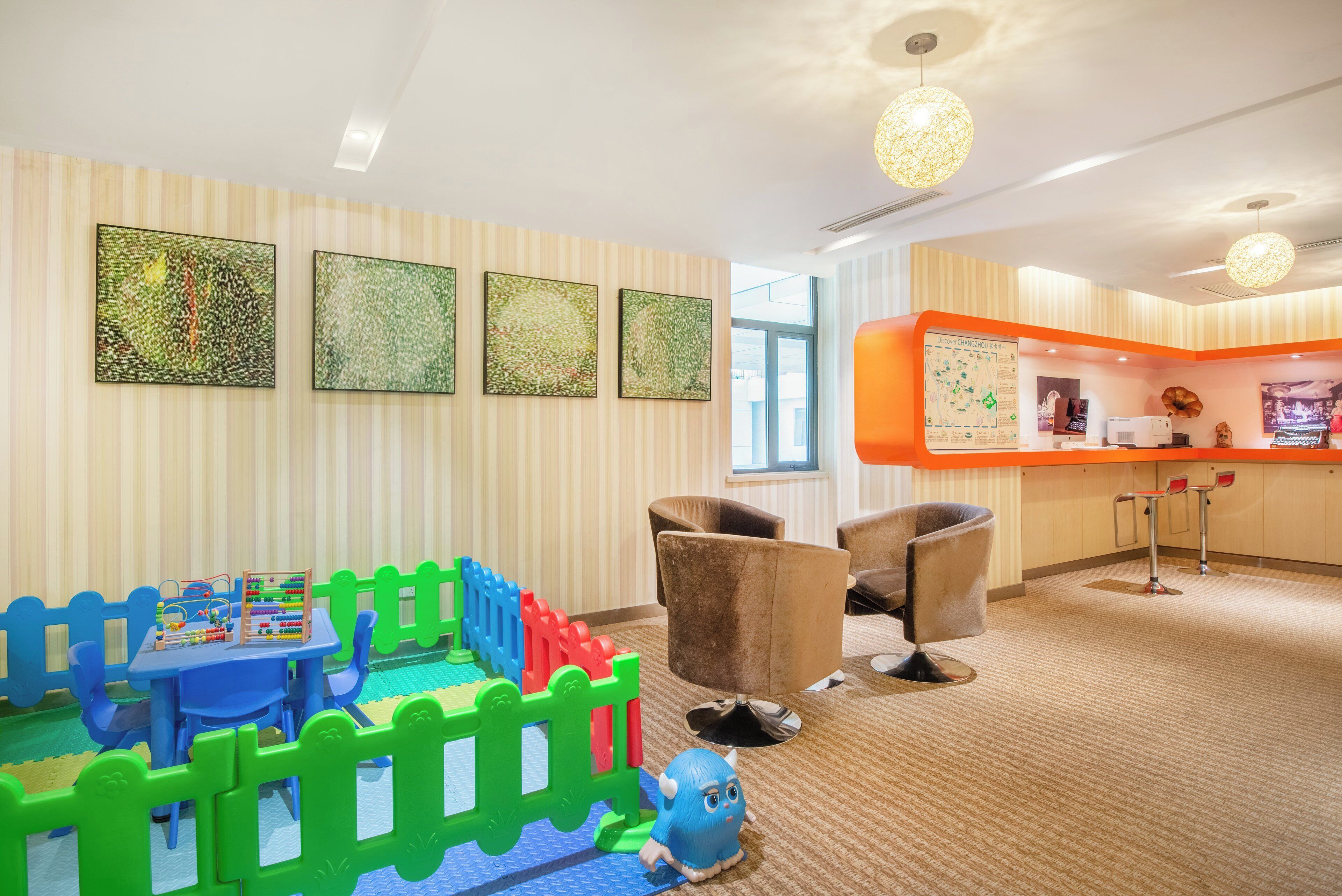 A children's play area with a blue table, colorful building blocks, and a blue toy. There are two brown chairs and a large orange counter with a map.