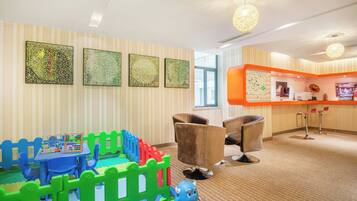 A children's play area with a blue table, colorful building blocks, and a blue toy. There are two brown chairs and a large orange counter with a map.