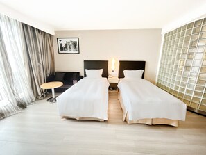 A hotel room with two single beds, a small round table, a sofa, and a wall-mounted picture. - Holiday Inn Express Changzhou Center by IHG (Changzhou)
