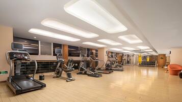 A modern gym with various cardio machines, a weightlifting area, and a clean, well-lit interior.